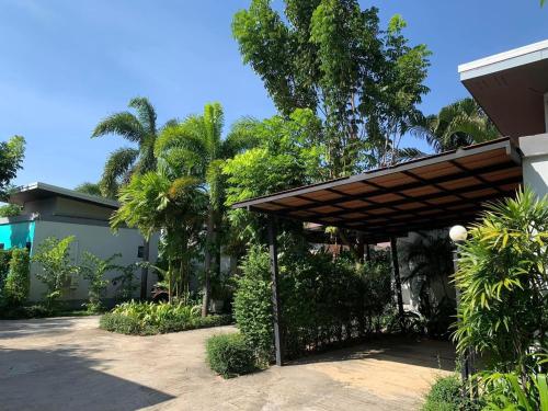 a house with a wooden pergola and palm trees at ยูสีเกด รีสอร์ท in Si Sa Ket