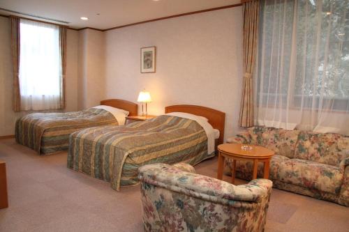 神戸市にある有馬 瑞宝園のベッド2台とソファが備わるホテルルームです。