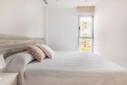 a white bedroom with a large bed with two pillows at Orilla del mar in Oliva