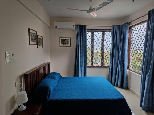 a bedroom with a blue bed and a window at Casa Do Mundo - Your Holiday Home in Porvorim