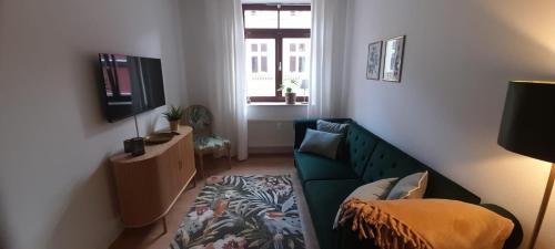 a living room with a green couch and a television at Suite - Mein Ankerplatz in Stralsund