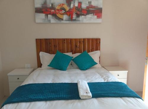 a bedroom with a bed with blue pillows at Matholeng Gardens Guesthouse in Foso