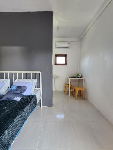 a bedroom with a bed and a table with a window at D'Flora Homestay in Labuan Bajo