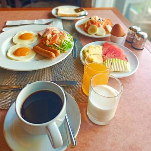 a table with plates of breakfast food and a cup of coffee at Mayflower Grande Suite Hotel in Phitsanulok