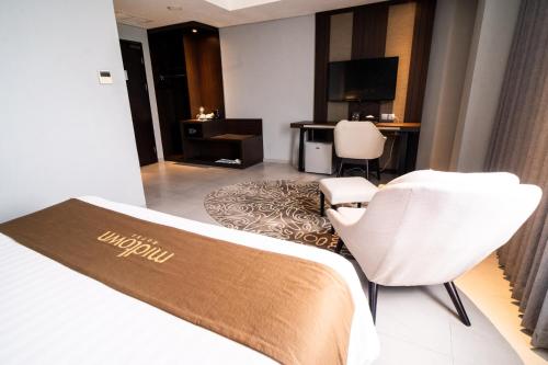 a hotel room with a bed and a chair and a television at Midtown Hotel Samarinda in Samarinda
