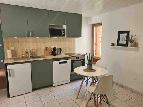 eine Küche mit grünen Schränken und einem Tisch mit Stühlen in der Unterkunft Joli appartement avec coin jardin in Chalon-sur-Saône