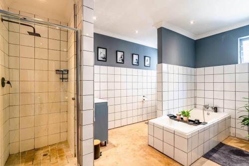 a bathroom with a shower and a tub and a sink at Cozy 2 bedroom garden cottage in Melville in Johannesburg