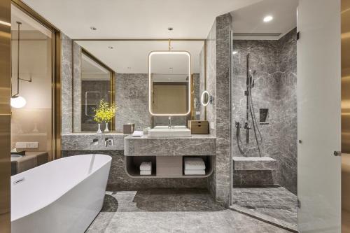 a bathroom with a tub and a sink and a mirror at Grand HiLai Taipei in Taipei
