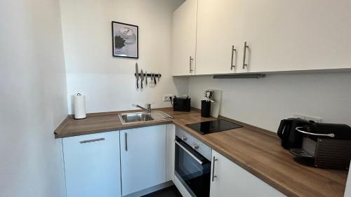 uma pequena cozinha com armários brancos e um lavatório em Skyview Studio Apartments at Berlin Kreuzberg-Mitte em Berlim