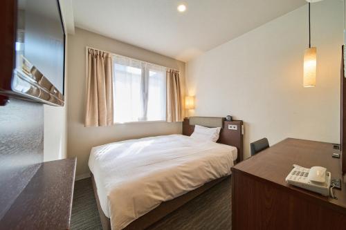 a bedroom with a bed and a desk with a phone at Via inn Kyoto Shijomuromachi in Kyoto