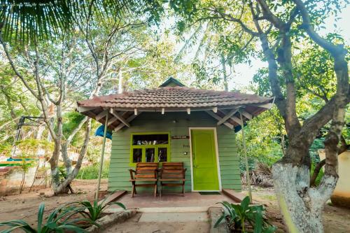 a small green house with a green door and chairs at Commune18 Resort Chikmagalur in Chikmagalūr