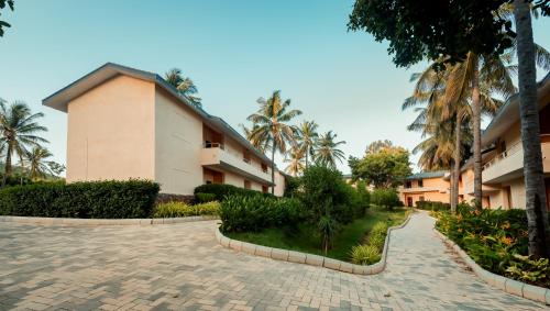 a building with palm trees and a brick driveway at Commune18 Resort Chikmagalur in Chikmagalūr