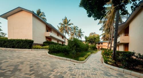 a building with palm trees and a brick driveway at Commune18 Resort Chikmagalur in Chikmagalūr