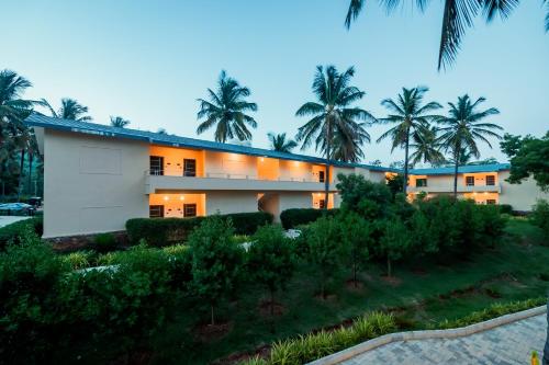a building with palm trees in front of it at Commune18 Resort Chikmagalur in Chikmagalūr