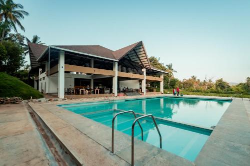 a swimming pool in front of a building at Commune18 Resort Chikmagalur in Chikmagalūr