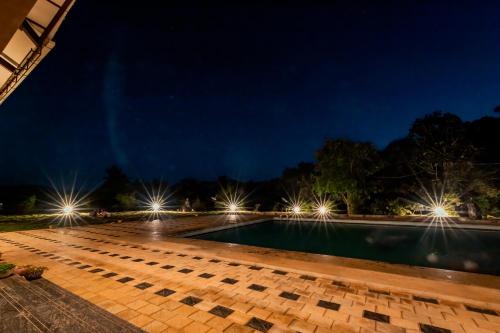 a swimming pool at night with lights at Commune18 Resort Chikmagalur in Chikmagalūr