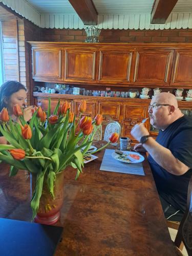 un hombre y una mujer sentados en una mesa con tulipanes en Kryzbarkas, en Degučiai