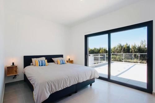 a bedroom with a large bed and a large window at Villa 33 Silver Coast in Nadadouro