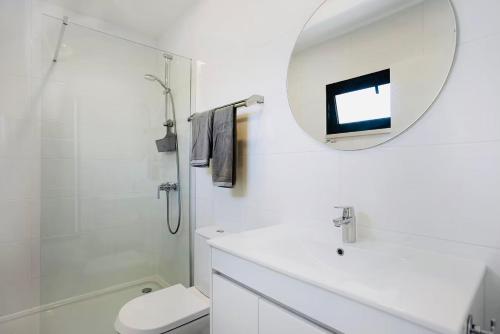 La salle de bains blanche est pourvue d'un lavabo et d'un miroir. dans l'établissement Villa 33 Silver Coast, à Nadadouro
