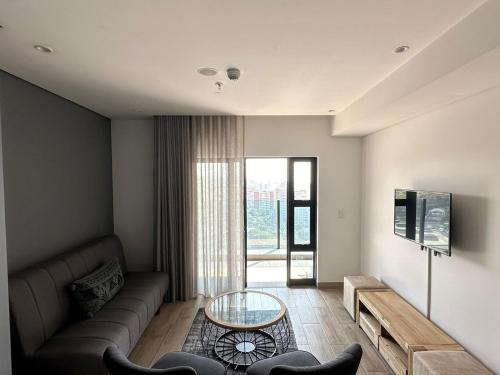 a living room with a couch and a glass table at Oceans Lux 1 Bedroom - Seaview in Durban