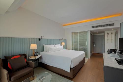a bedroom with a bed and a chair and a desk at The Boathouse Phuket-SHA Plus in Kata Beach