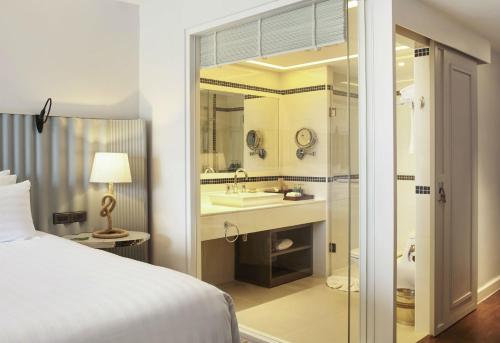 a bedroom with a bed and a bathroom with a sink at The Boathouse Phuket-SHA Plus in Kata Beach