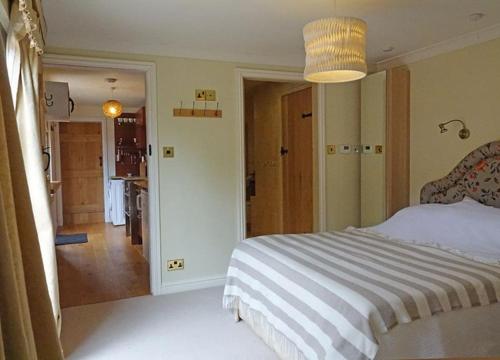 a bedroom with a large bed and a hallway at Country garden retreat near Henley on Thames in Rotherfield Peppard