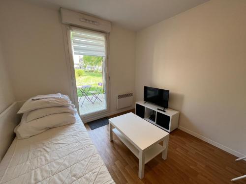 a bedroom with a bed and a tv and a window at Acajou, Studio avec terrasse et parking privé in Caen