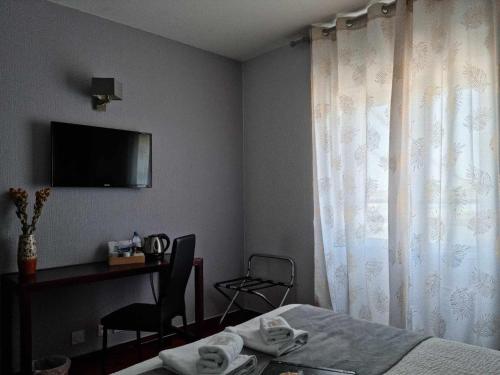 a hotel room with a bed and a desk and a television at Logis Hotel Schaeffer- Restaurant Le Saint Georges in Serrières