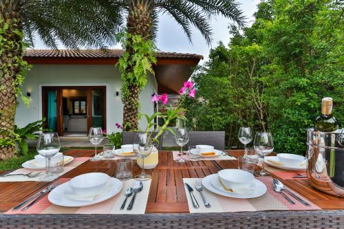 a wooden table with white plates and wine glasses at Cliff Haven Villa Krabi in Ao Nang Beach