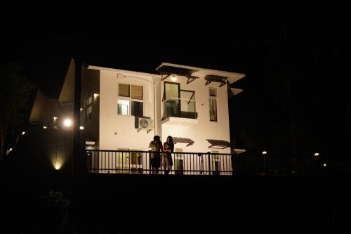 two people standing on a balcony of a house at night at Pabis luxurious stay in Vythiri