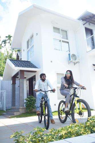 two people riding bikes in front of a house at Pabis luxurious stay in Vythiri
