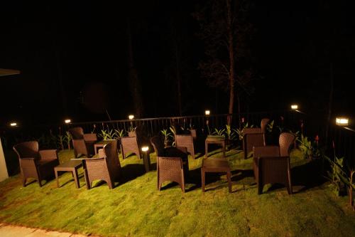 a group of chairs sitting on the grass at night at Pabis luxurious stay in Vythiri