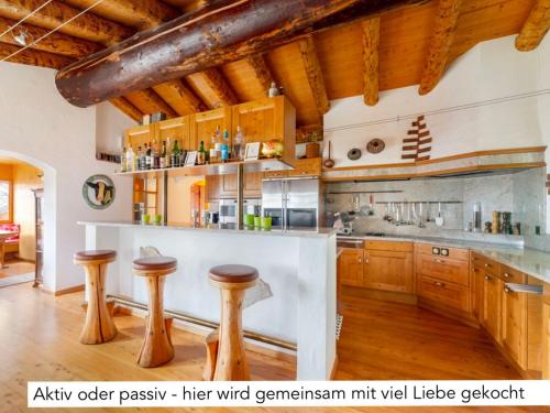 a kitchen with wooden cabinets and a counter with stools at Chalet Müsli in Wildhaus