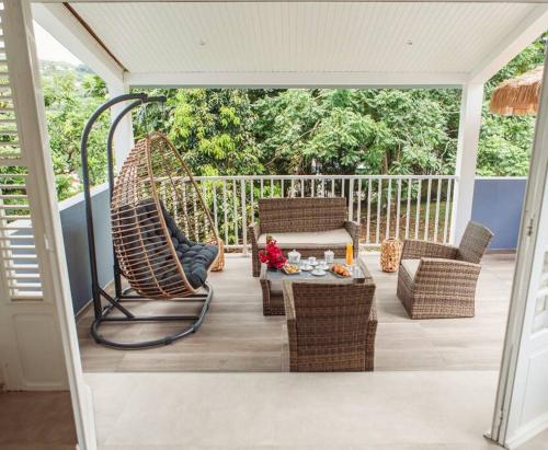 a porch with wicker chairs and a table on a deck at Villa F4 chic avec jacuzzi en Martinique in Le Lamentin