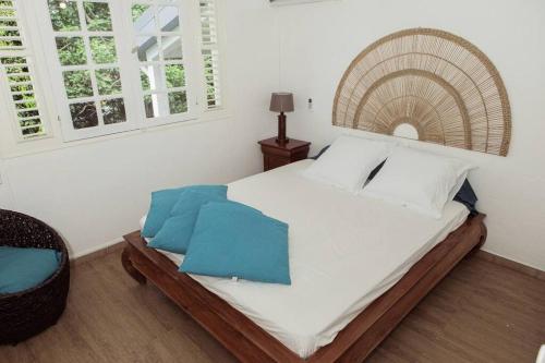 1 dormitorio con 1 cama grande con sábanas blancas y almohadas azules en Villa F4 chic avec jacuzzi en Martinique en Le Lamentin