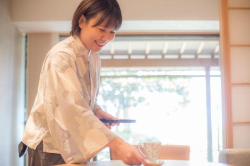 a woman is preparing food in a kitchen at Hotel Kitanoya in Miyazu