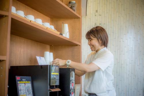 a man is putting a piece of paper into a refrigerator at Hotel Kitanoya in Miyazu