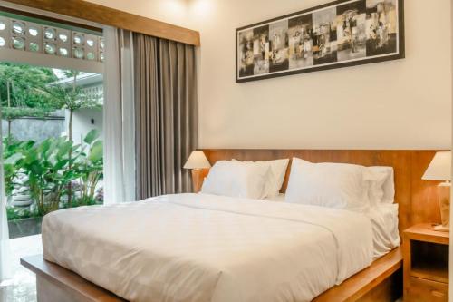 a bedroom with a white bed and a large window at sayana bali in Gianyar