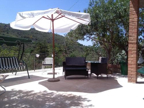 un patio con mesa, sombrilla y sillas en Dimora Buglio Valguarnera, en Valguarnera Caropepe