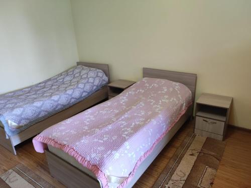 two beds in a room with two tables at Гостевой Дом Чолпон-Ата in Cholpon-Ata