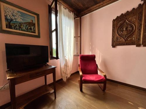 a living room with a red chair and a television at Ca' De Franceschi in Teolo