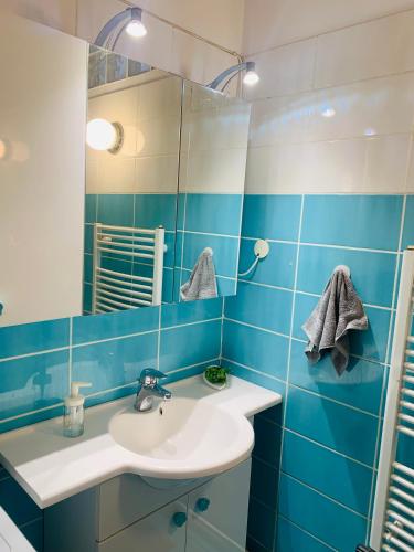 a blue tiled bathroom with a sink and a mirror at Peaceful Haven in Budapest