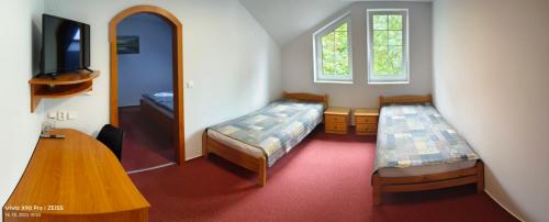 Habitación con 2 camas, mesa y espejo. en Penzion YORK, en Liberec