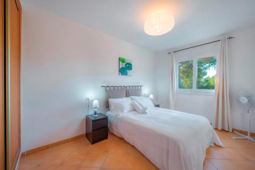 a white bedroom with a bed and a window at Villa Cala Pi in Cala Pi