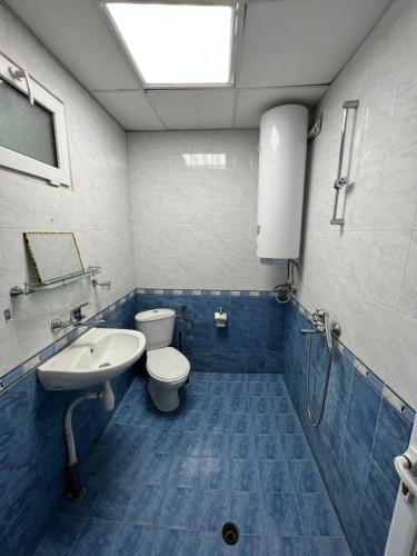 a blue tiled bathroom with a toilet and a sink at Почивна база Пиринпласт in Gotse Delchev