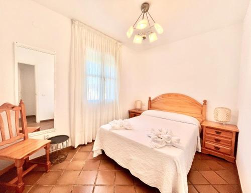 ein Schlafzimmer mit einem Bett, einem Stuhl und einem Fenster in der Unterkunft Las Terrazas Islantilla in Huelva