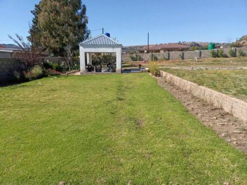 um jardim com um gazebo num campo em Matholeng Gardens Guesthouse em Foso