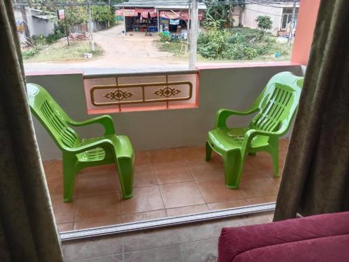 two green chairs sitting in a room with a window at Praew Guesthouse in Phra Ae beach