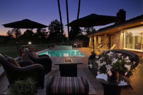 a patio with chairs and a swimming pool with umbrellas at Cottage On The Greens - Studio in Poway